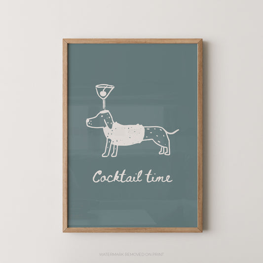 Framed wall art print with a dachshund illustration balancing a cocktail glass on its head and the words 'Cocktail time' below, shown against a light neutral wall.