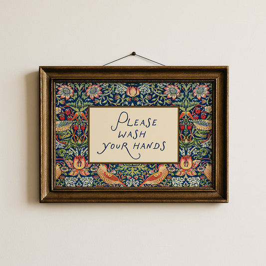 Decorative framed sign with floral pattern and 'Please Wash Your Hands' text on a plain wall.