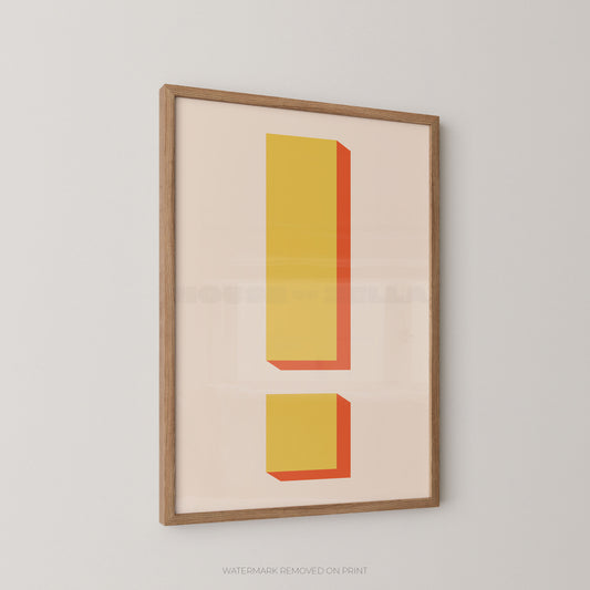 a bold graphic exclamation mark print in yellow and orange, framed in an oak frame hung on a light wall