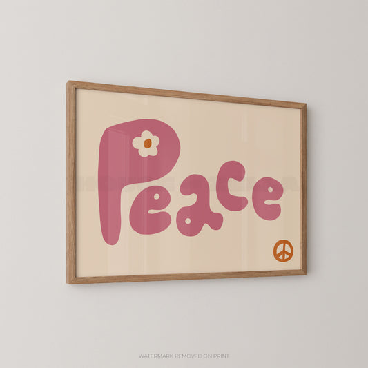 A framed retro-style art print featuring the word 'Peace' in pink bubble letters with a small white flower on the letter 'P', plus a small orange peace symbol in the lower right. The print is mounted in a light wood frame and hangs on a plain light gray wall.