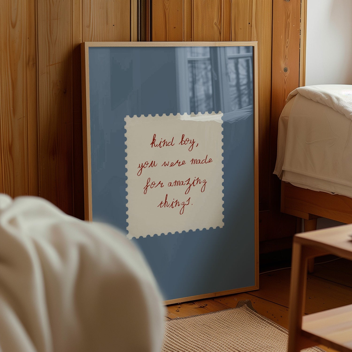 House of Zella quote wall art print in a blue frame styled beside a bed in a cosy bedroom interior.