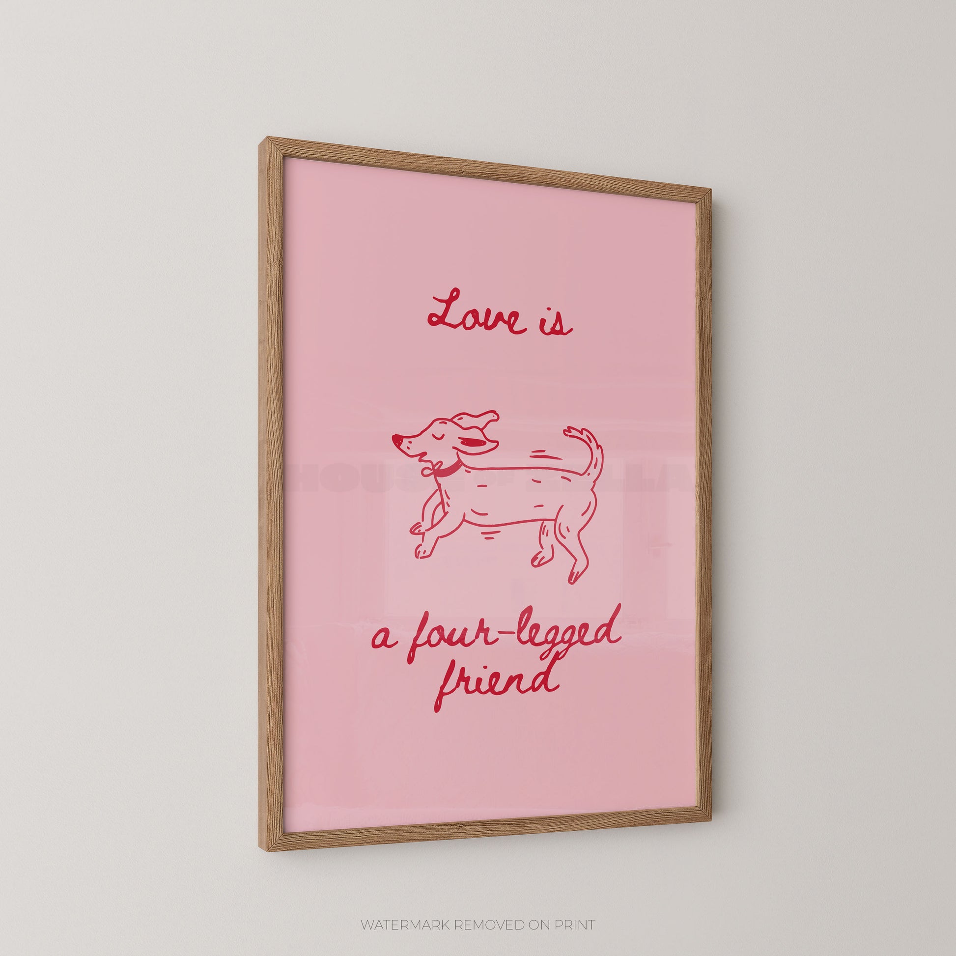 A framed art print featuring a pink background with a red line drawing of a dog and the text 'Love is a four-legged friend' in red script, displayed on a light gray wall.