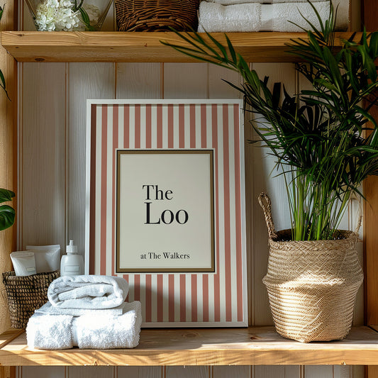 Framed picture with striped border and text on a wooden shelf with towels and plants.