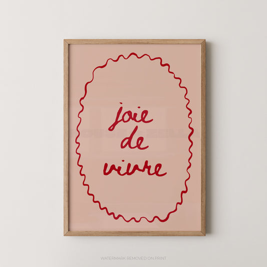 A framed wall art print with the French phrase “joie de vivre” in red script inside a red wavy oval border, set in a light wood frame against a plain light gray wall.