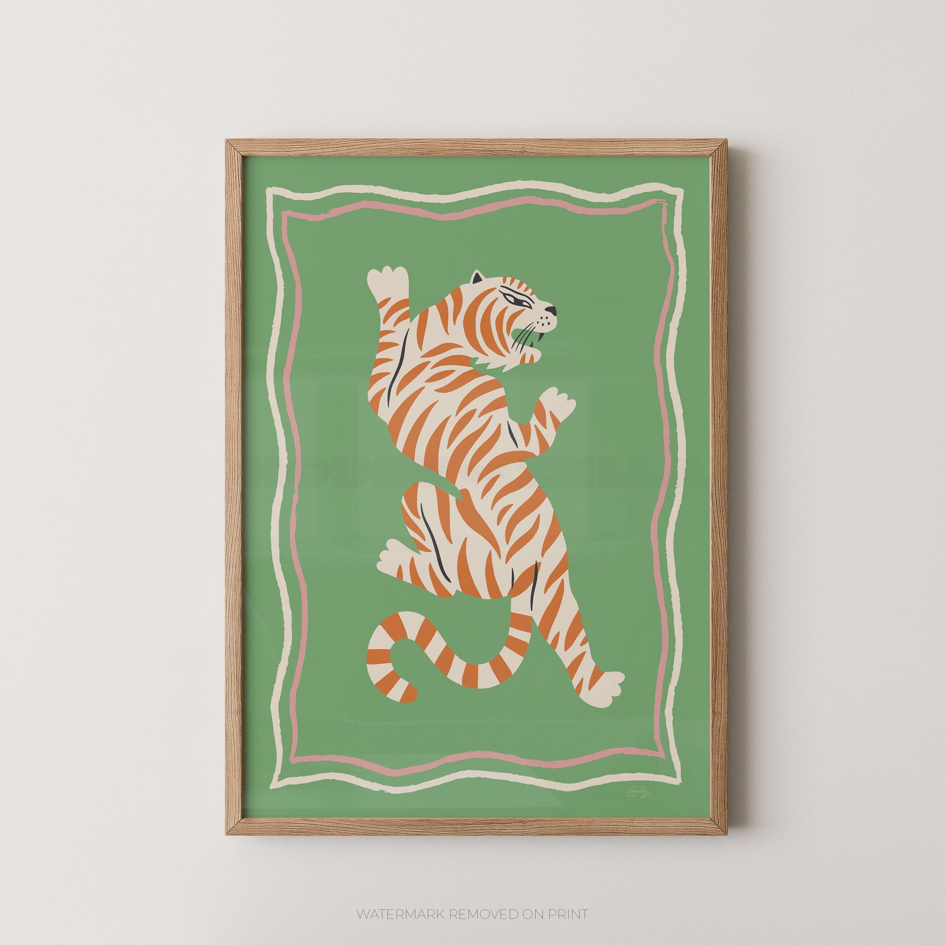 Framed wall art featuring a stylized orange tiger with black stripes on a green background, enclosed in a light wood frame against a white wall.