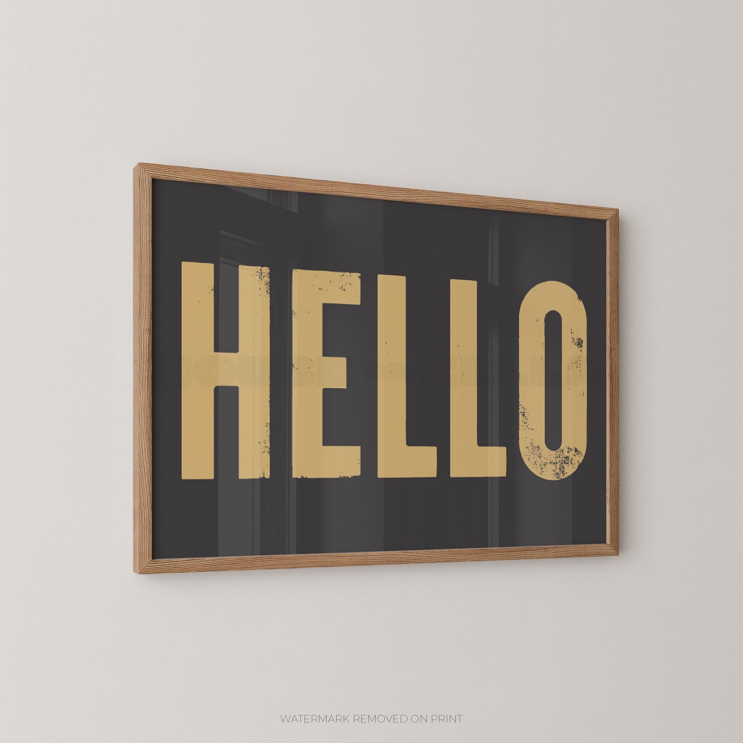 Framed wall art print with the word "HELLO" in large distressed gold letters on a dark charcoal background, shown hanging on a light gray wall.