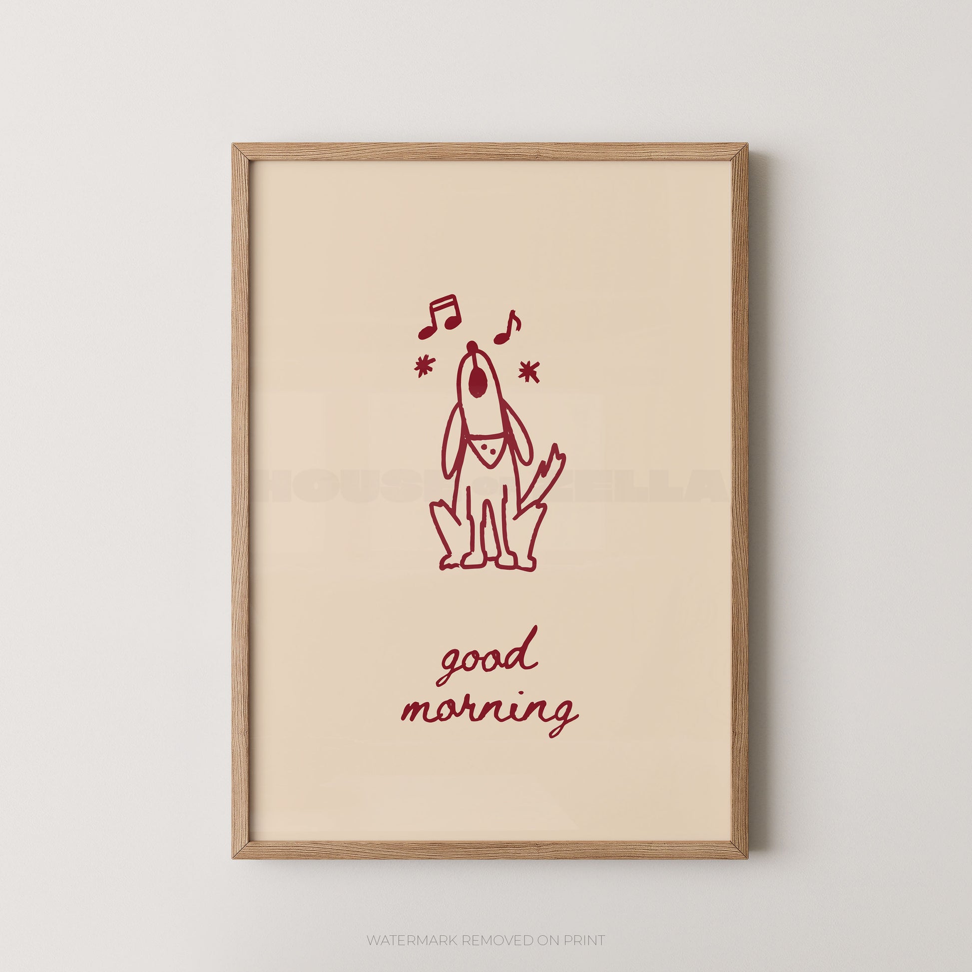 A framed art print featuring a minimalist red line drawing of a dog with musical notes and the words 'good morning' in red script on a warm cream background, enclosed in a light natural wood frame.