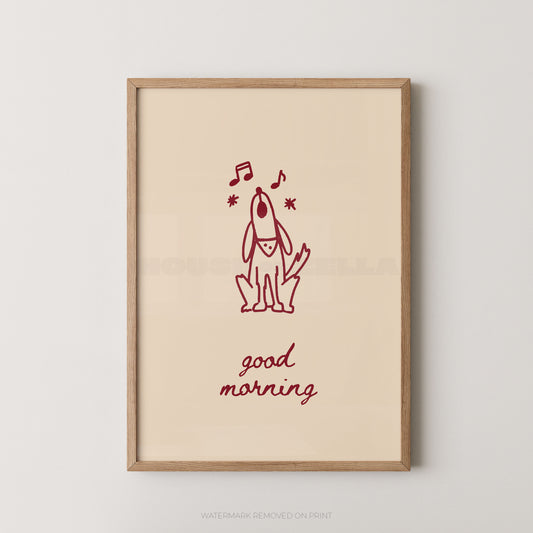A framed art print featuring a minimalist red line drawing of a dog with musical notes and the words 'good morning' in red script on a warm cream background, enclosed in a light natural wood frame.