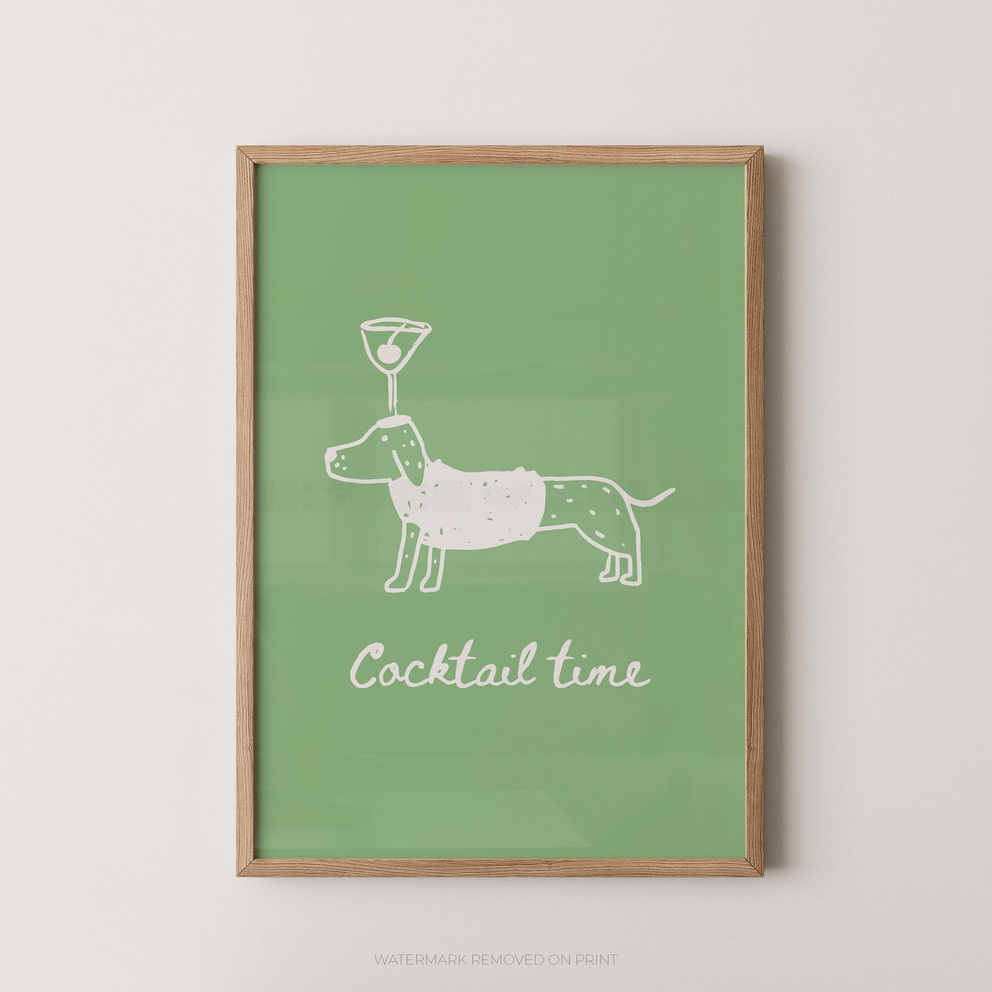 A framed art print featuring a white line drawing of a dachshund holding a cocktail on its head, with the text 'Cocktail time' below, set against a solid sage green background and enclosed in a light wood frame.