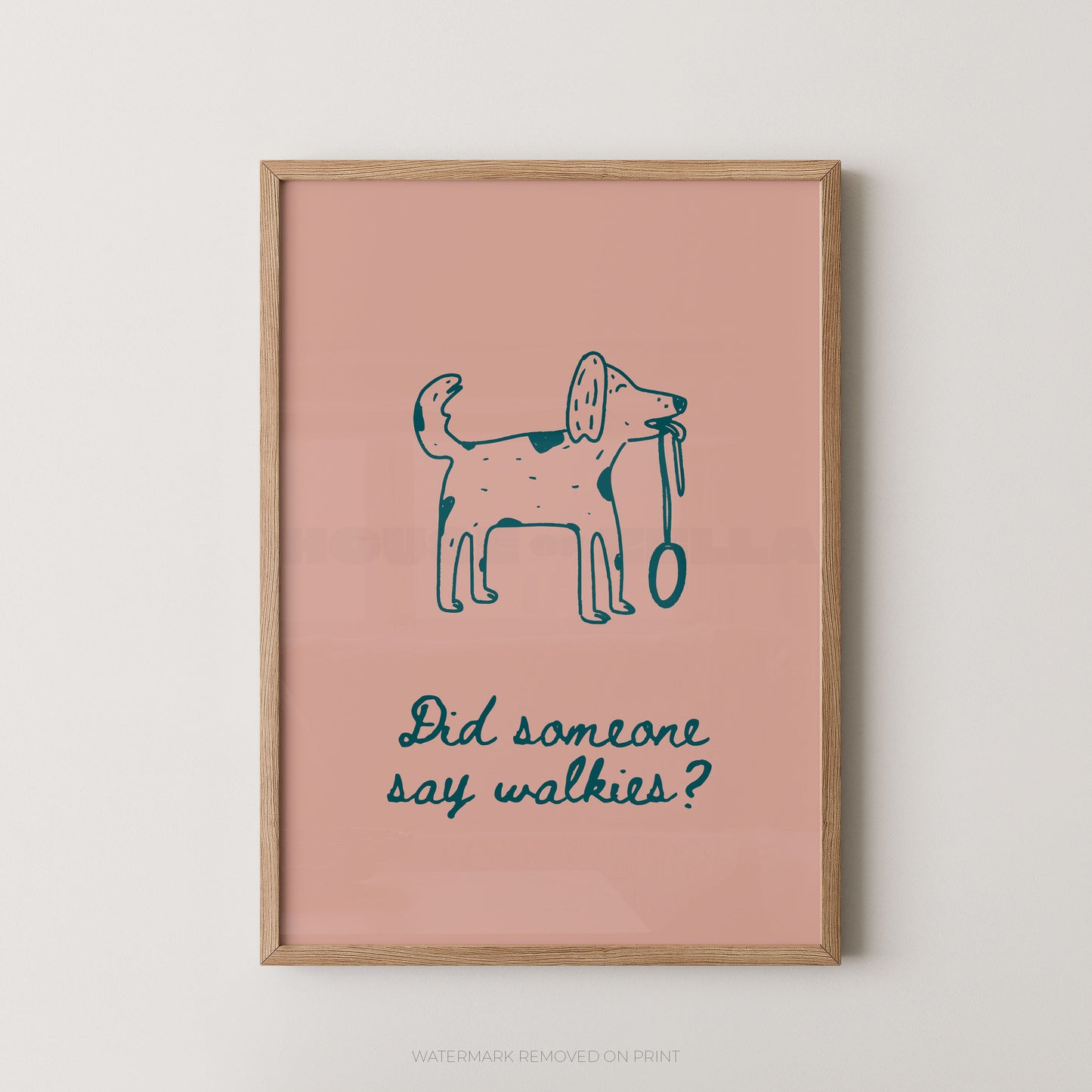 A framed art print featuring a simple blue line drawing of a dog holding a leash on a dusty pink background, with the text 'Did someone say walkies?' below. The print is housed in a light natural wood frame and is displayed against a neutral light gray wall.