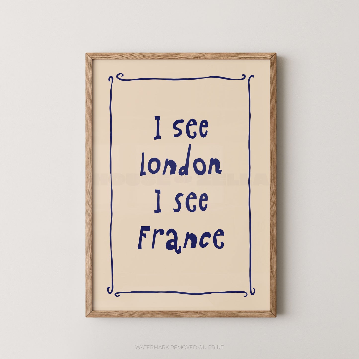 Framed typographic wall art hanging on a light neutral wall. The print has a cream background with dark blue handwritten-style text reading 'I see London I see France' inside a thin blue decorative border, surrounded by a light natural wood frame.