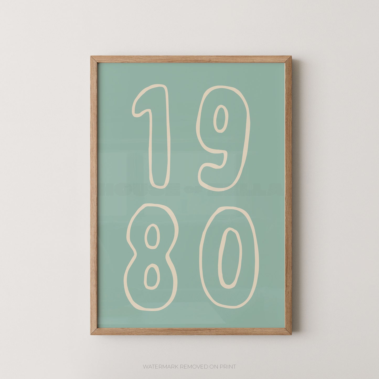 A framed minimalist art print featuring the numbers '1980' in cream outline font on a muted teal-green background, enclosed in a light natural wood frame against a light gray wall.