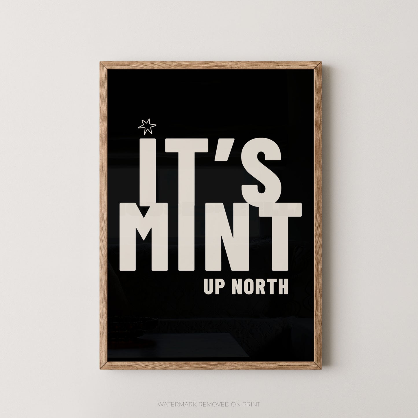 Framed typographic wall art with a light wood frame, black background, and large white text reading “IT’S MINT UP NORTH,” shown hanging on a light neutral wall.