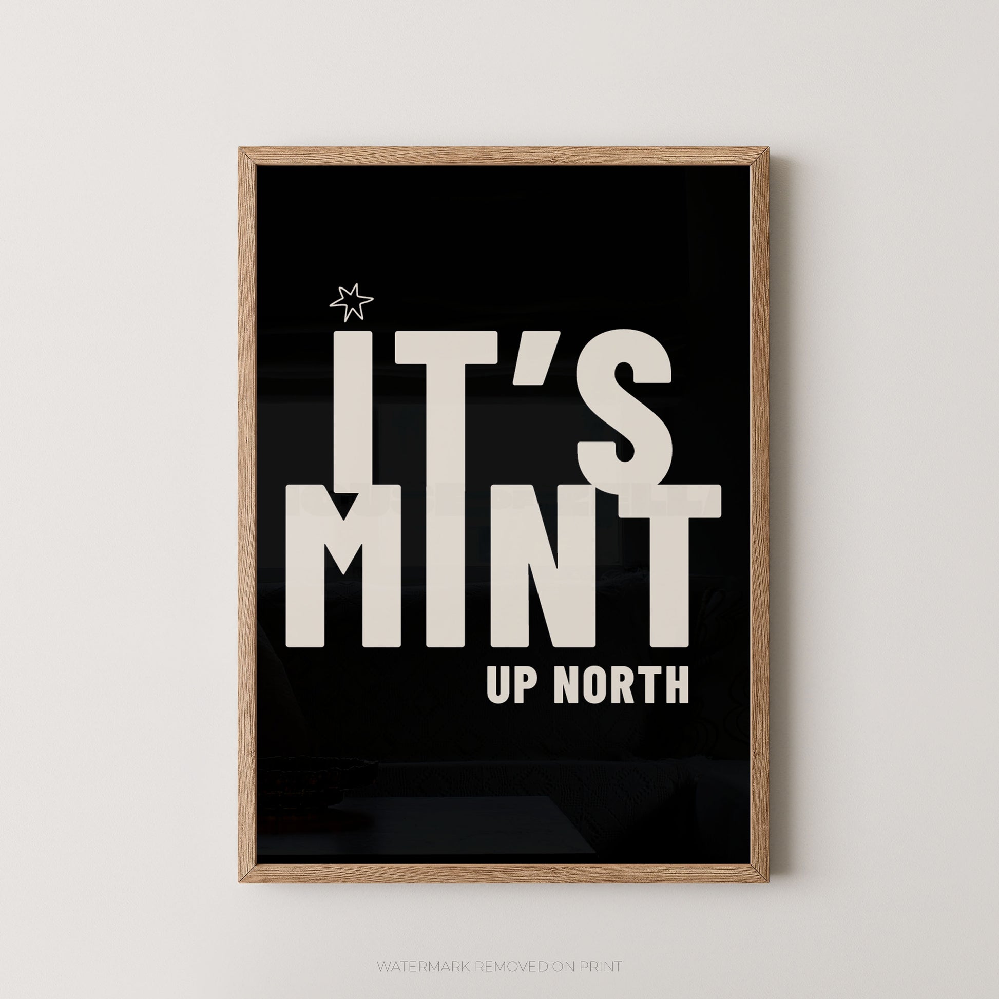 Framed typographic wall art with a light wood frame, black background, and large white text reading “IT’S MINT UP NORTH,” shown hanging on a light neutral wall.