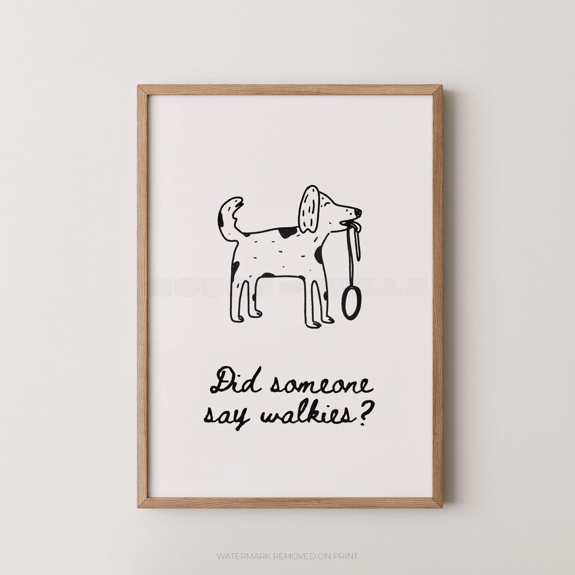 A framed wall art print featuring a simple black line drawing of a dog holding a leash, with the text 'Did someone say walkies?' below. The print has a white background and is enclosed in a light natural wood frame, shown against a light gray wall.