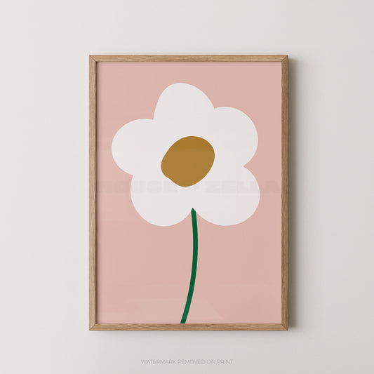 Framed minimalist wall art featuring a stylized white flower with a gold center and green stem on a dusty pink background, shown hanging on a light neutral wall.