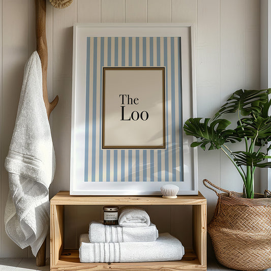 Framed artwork with striped design and text on a wooden shelf with folded towels and a plant.