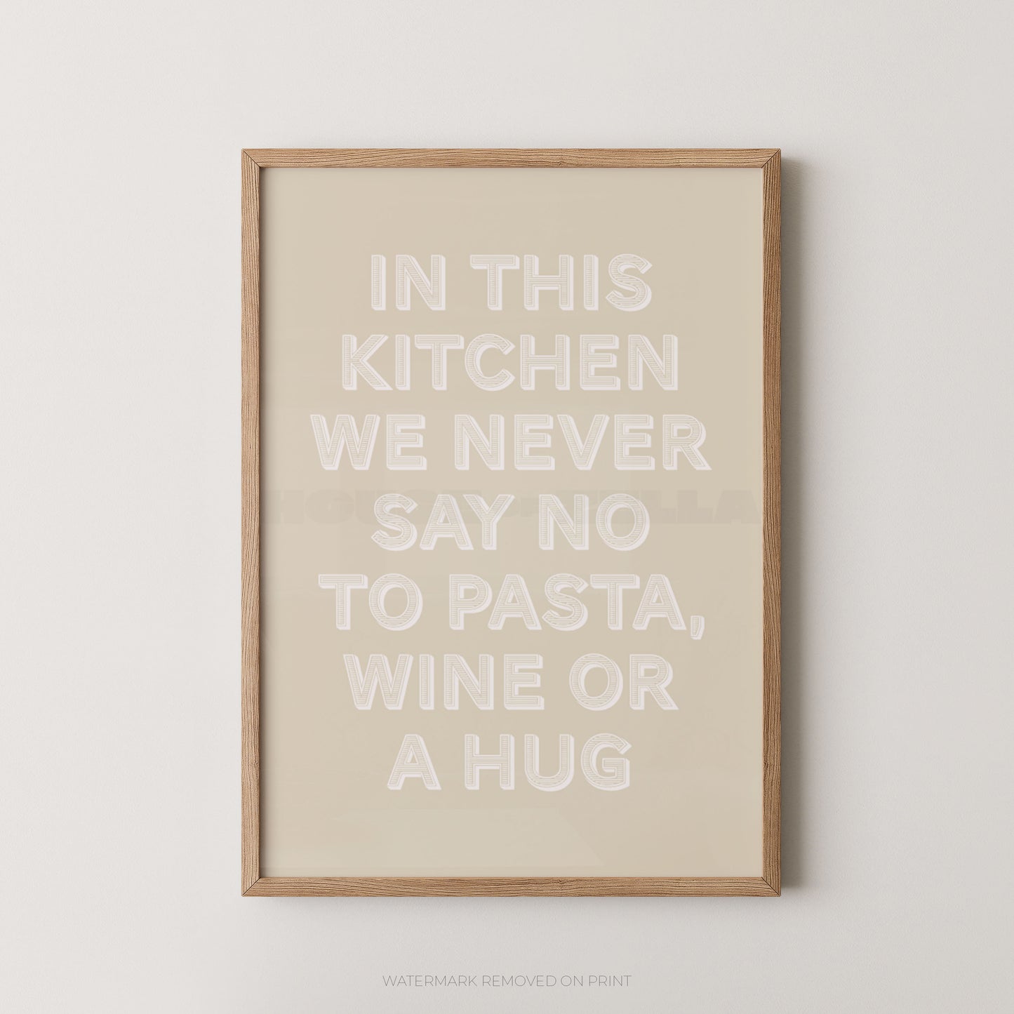 A framed typographic wall art print with the phrase “IN THIS KITCHEN WE NEVER SAY NO TO PASTA, WINE OR A HUG” in large white letters on a warm beige background, shown hanging against a light neutral wall.