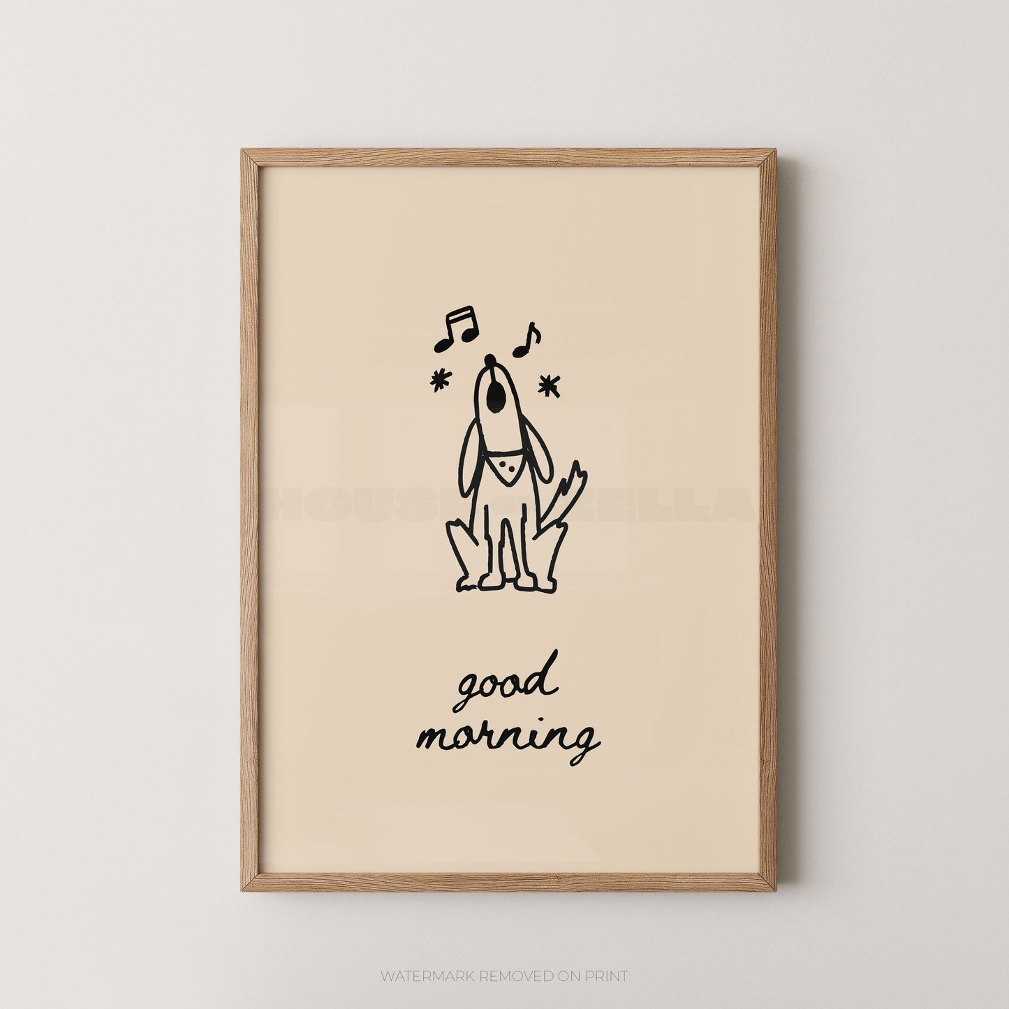 A framed art print featuring a minimalist black line drawing of a dog with musical notes and the text 'good morning' on a warm cream background, enclosed in a light natural wood frame against a neutral light gray wall.