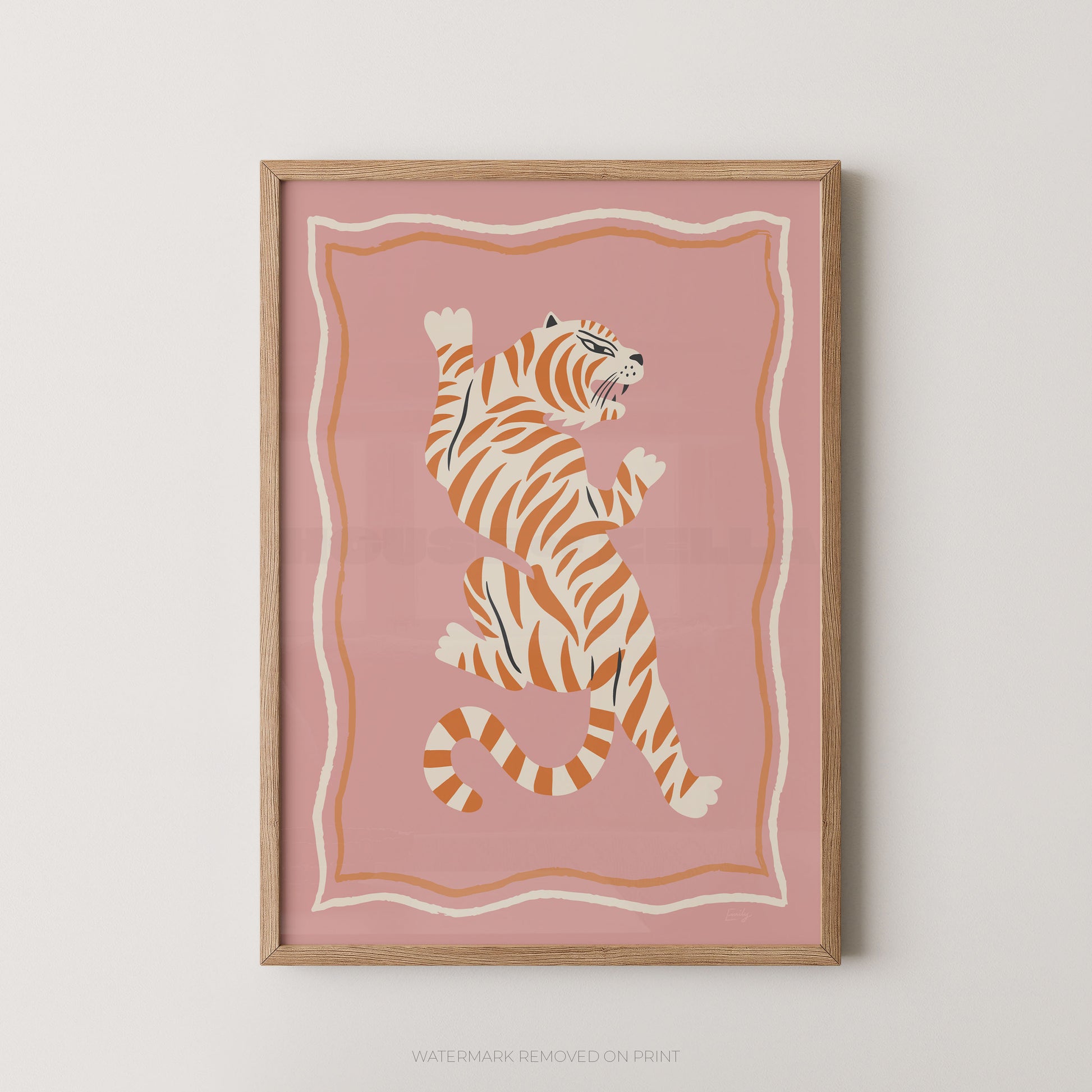 Framed wall art featuring a stylized orange and cream tiger on a dusty pink background, shown hanging against a light neutral wall.