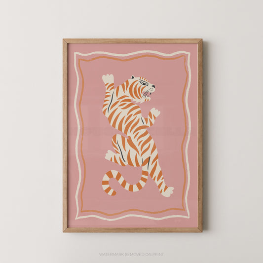 Framed wall art featuring a stylized orange and cream tiger on a dusty pink background, shown hanging against a light neutral wall.