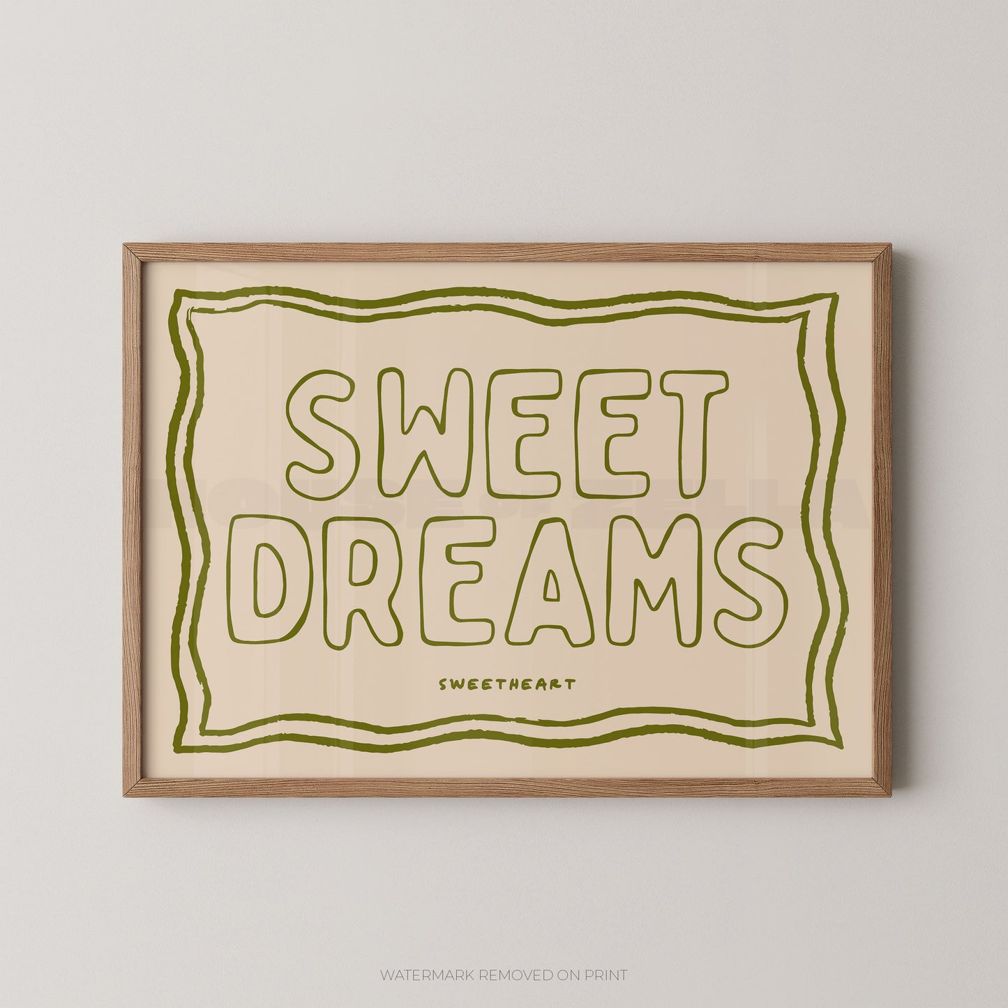 Framed typographic wall art reading “SWEET DREAMS” in olive green outline lettering on a warm cream background, with a light natural wood frame, shown against a light gray wall.