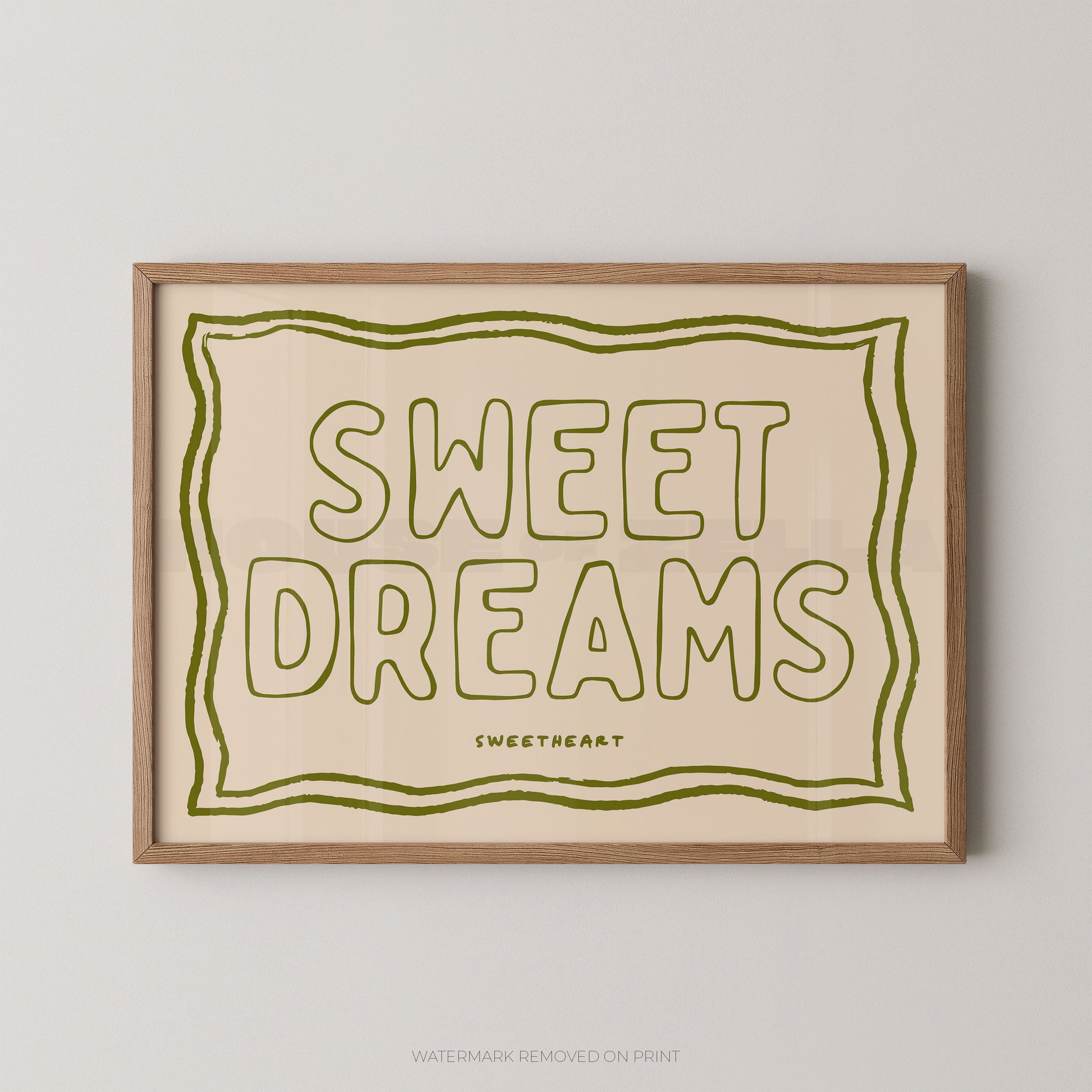 Framed typographic wall art reading “SWEET DREAMS” in olive green outline lettering on a warm cream background, with a light natural wood frame, shown against a light gray wall.