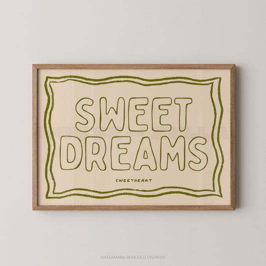 Framed typographic wall art reading “SWEET DREAMS” in olive green outline lettering on a warm cream background, with a light natural wood frame, shown against a light gray wall.