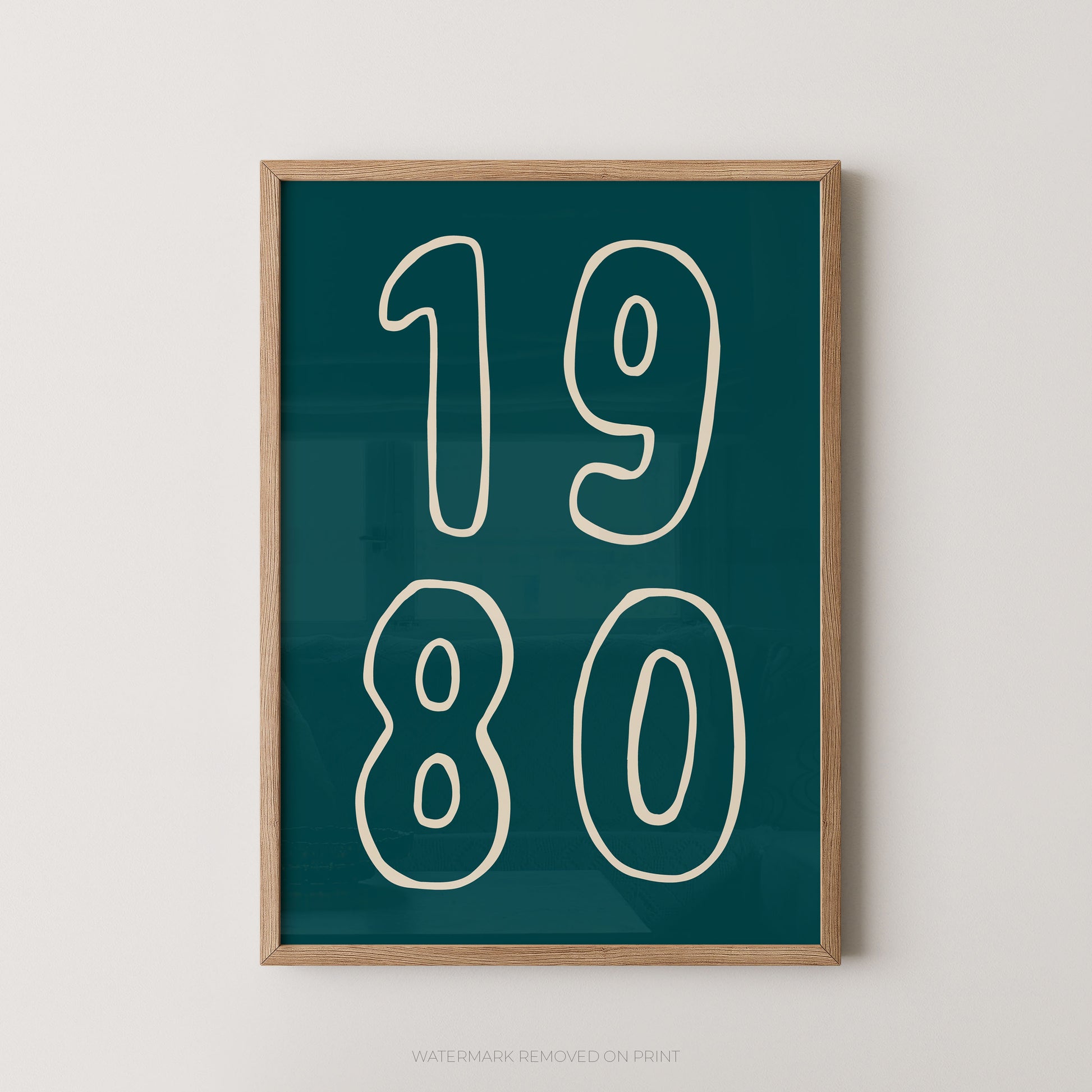Framed wall art print with the numbers '1980' in white outlined font on a dark teal background, shown hanging against a light neutral wall.
