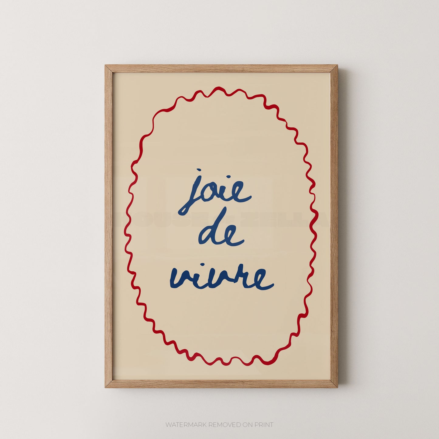 Framed wall art print with the French phrase “joie de vivre” in blue script inside a red wavy oval border, set in a light wood frame against a light gray wall.