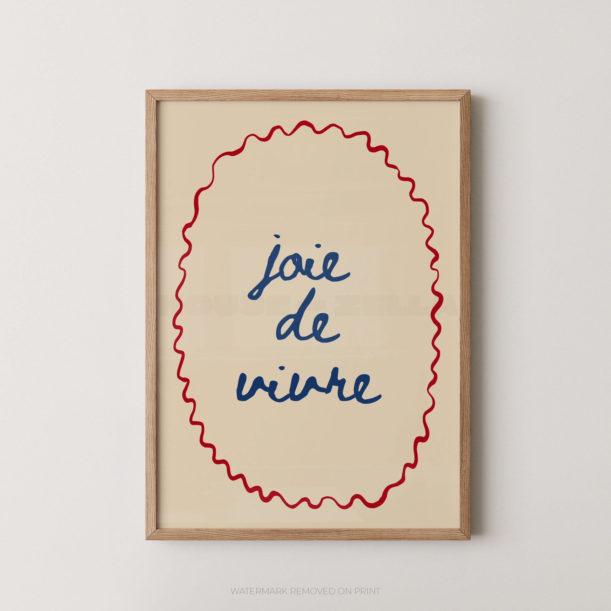 Framed wall art print with the French phrase “joie de vivre” in blue script inside a red wavy oval border, set in a light wood frame against a light gray wall.
