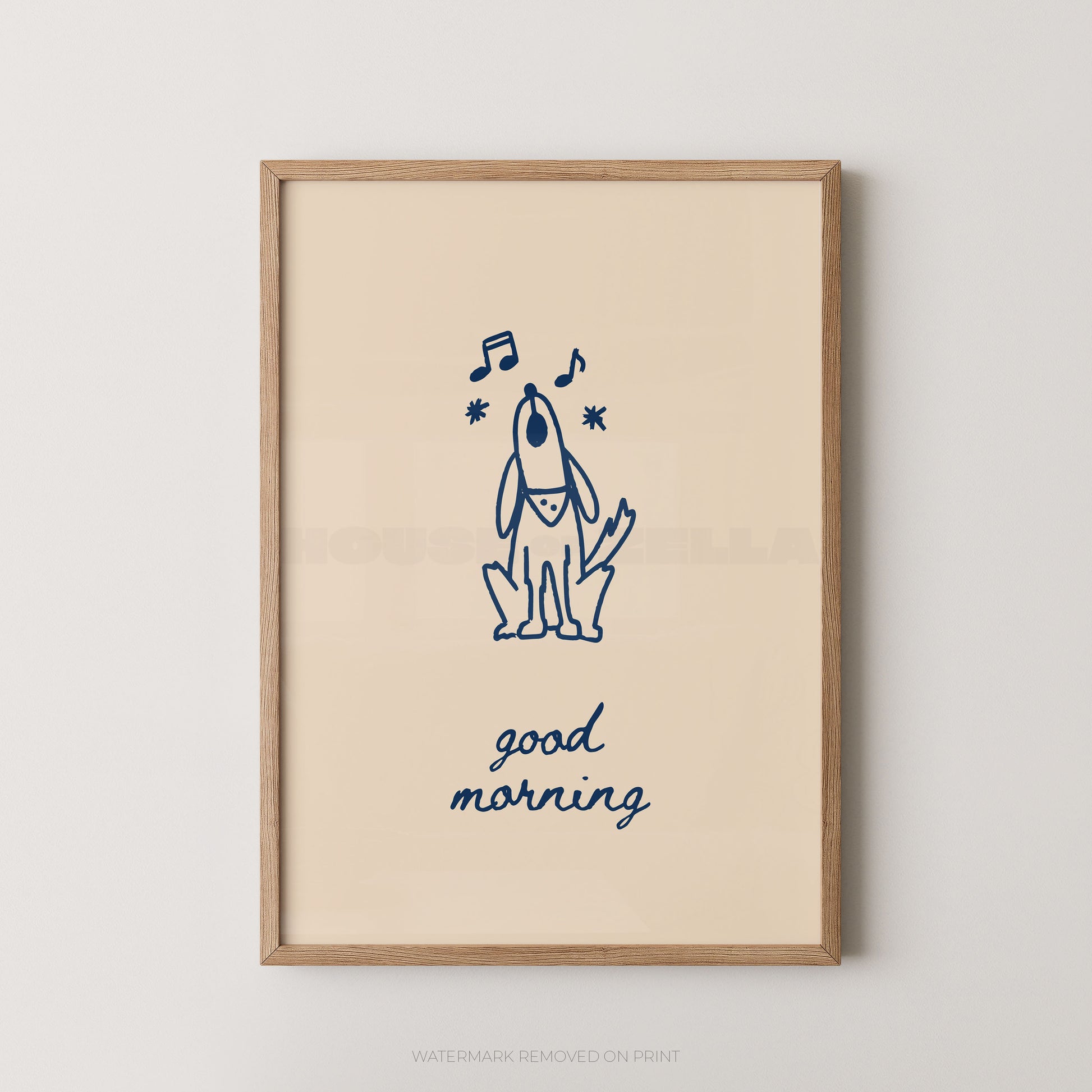 A framed art print featuring a navy blue line drawing of a dog with musical notes and the text 'good morning' on a warm cream background, enclosed in a light wood frame against a neutral wall.