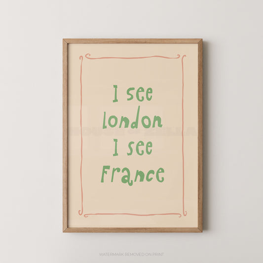 Framed typographic wall art print with the text 'I see London I see France' in green handwritten-style lettering on a warm cream background, bordered by a thin coral line and a light natural wood frame, shown against a light gray wall.