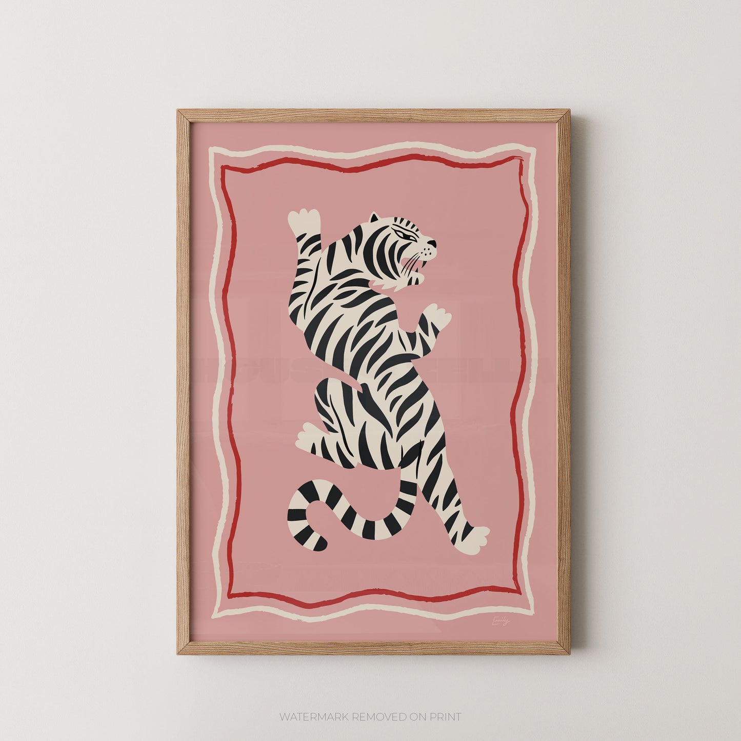 Framed wall art featuring a stylized black-and-white tiger on a pink background with red and cream border lines, shown hanging against a light neutral wall.