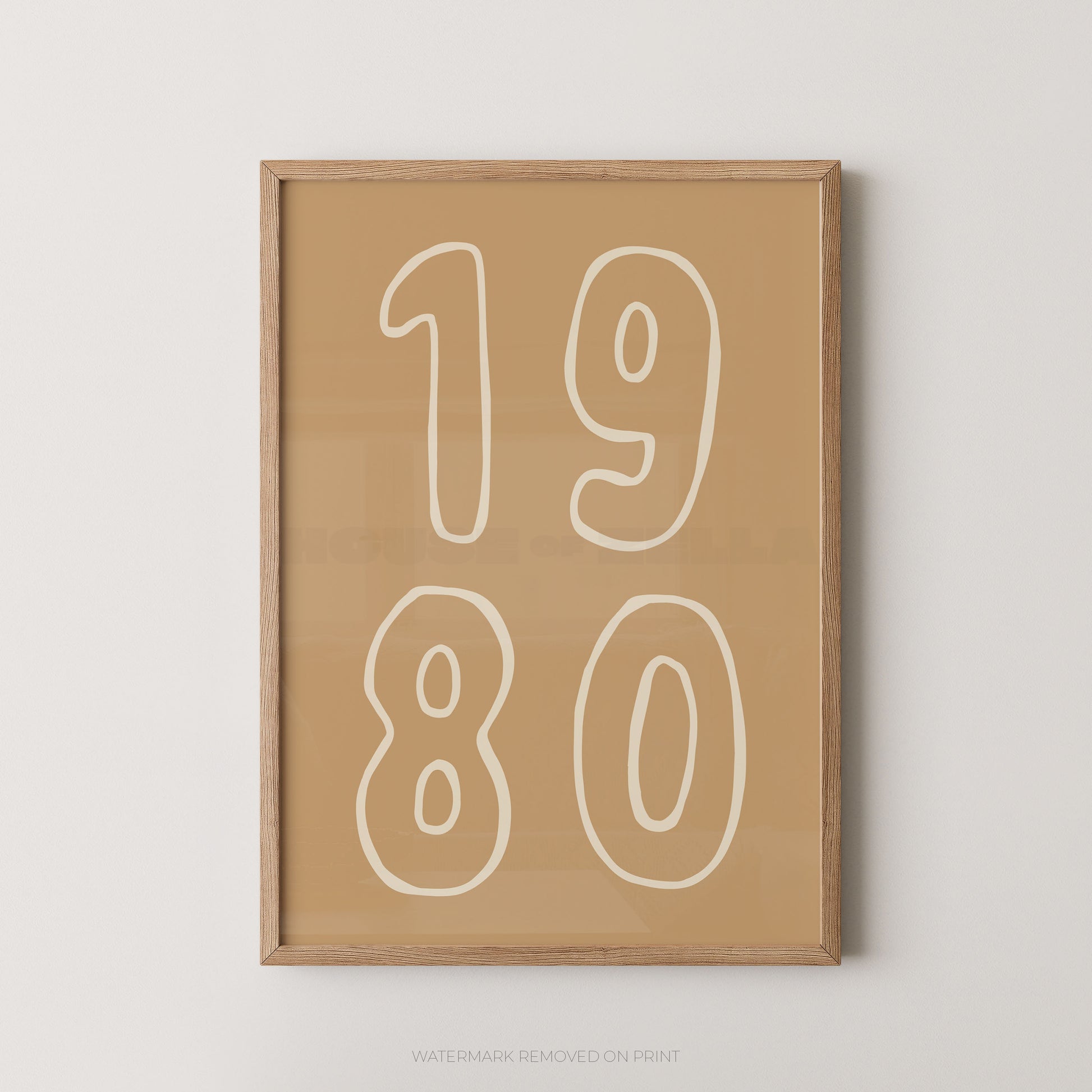 A framed minimalist art print featuring the numbers '1980' in white outline font on a warm tan background, enclosed in a light natural wood frame and shown against a neutral light gray wall.