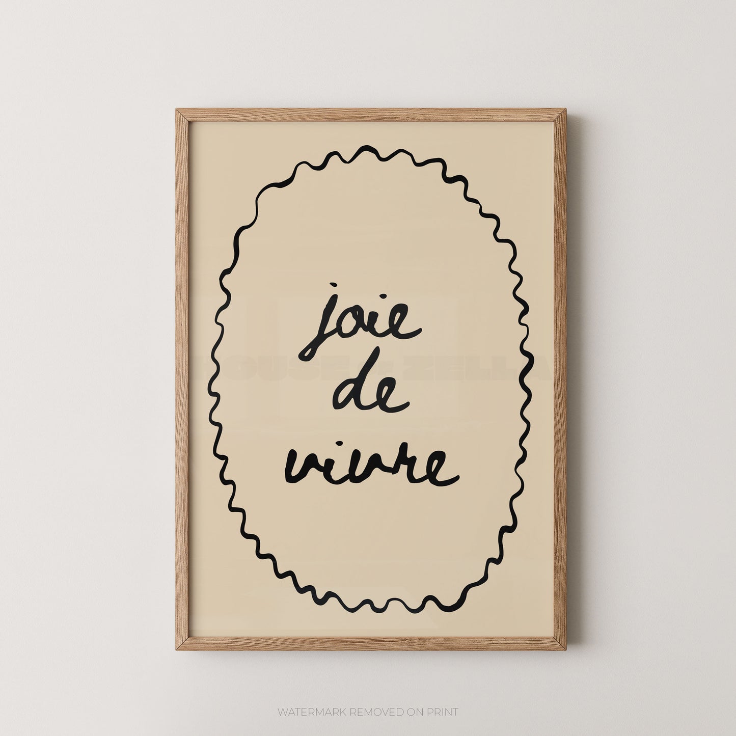 Framed wall art print with the French phrase “joie de vivre” in black script inside a wavy oval border, shown in a light wood frame against a plain light gray wall.