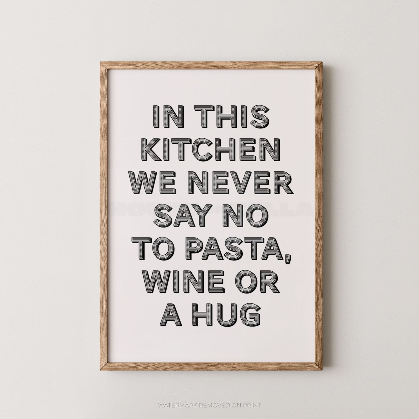 A framed typographic wall art print with the phrase “IN THIS KITCHEN WE NEVER SAY NO TO PASTA, WINE OR A HUG” in large gray letters on a white background, shown hanging against a light gray wall.