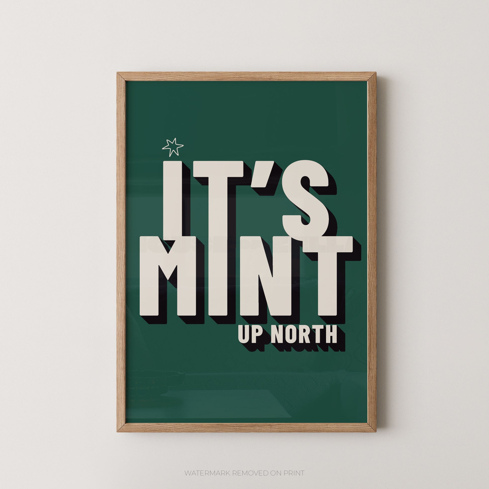 Framed typographic wall art with the phrase “IT’S MINT UP NORTH” in large cream letters on a dark green background, shown hanging against a light neutral wall.