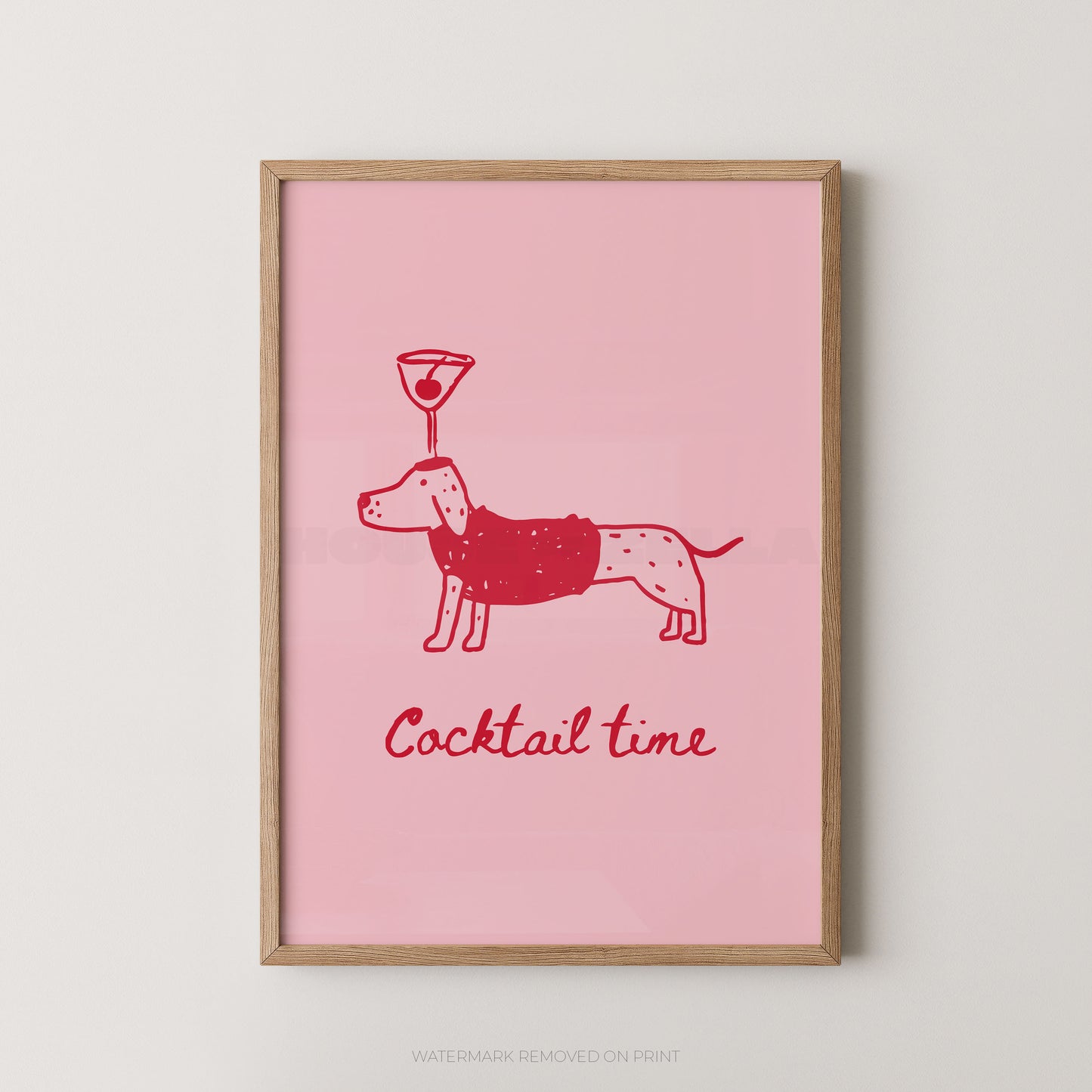 A framed art print featuring a pink background with a red line drawing of a dachshund wearing a sweater and balancing a cocktail glass on its head, with the text 'Cocktail time' below. The print is housed in a light natural wood frame and is displayed against a neutral light gray wall.