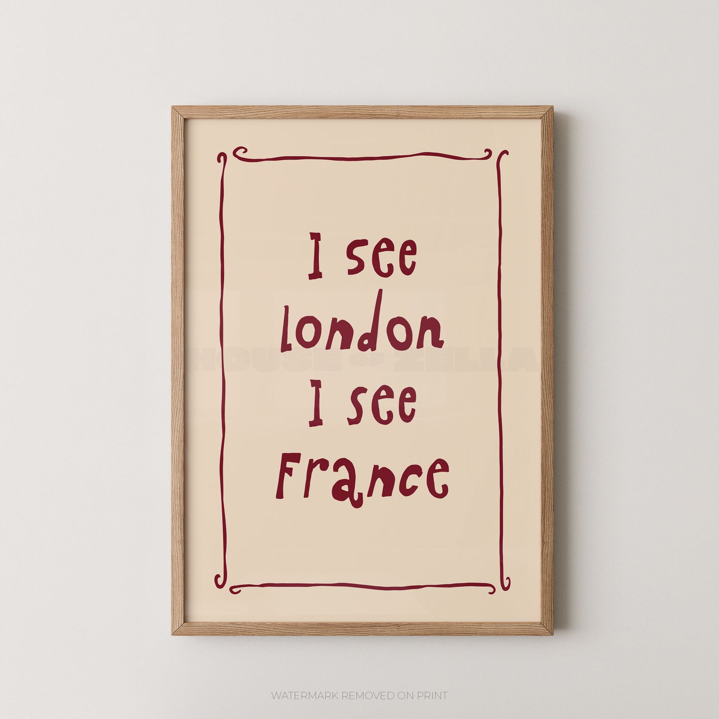 Framed typographic wall art hanging on a light gray wall, featuring the phrase 'I see London I see France' in dark red lettering inside a thin decorative red border on a warm cream background.