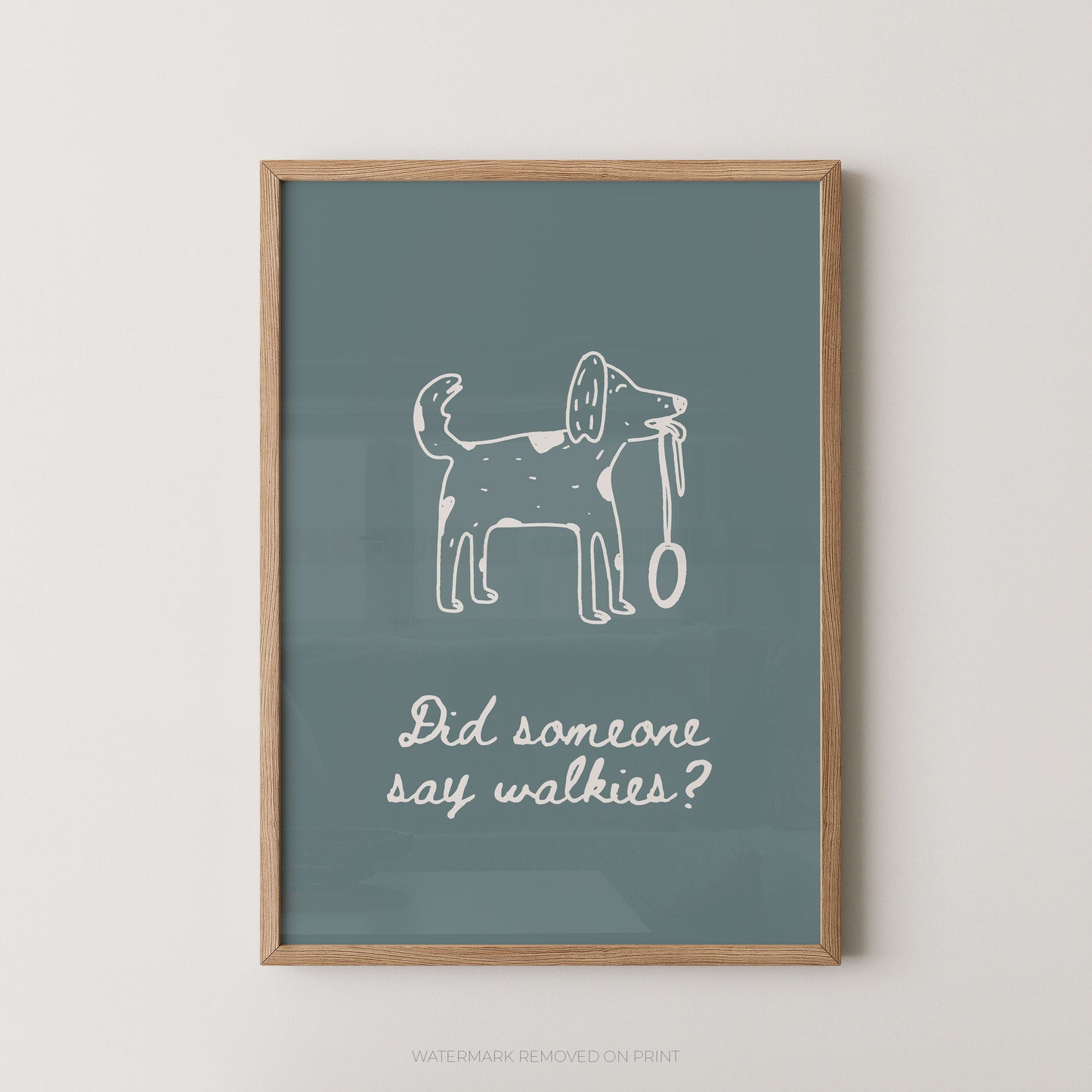A framed wall art print with a muted blue-green background, a white line drawing of a dog holding a leash, and the phrase 'Did someone say walkies?' in white script. The print is shown in a light wood frame against a plain light wall.