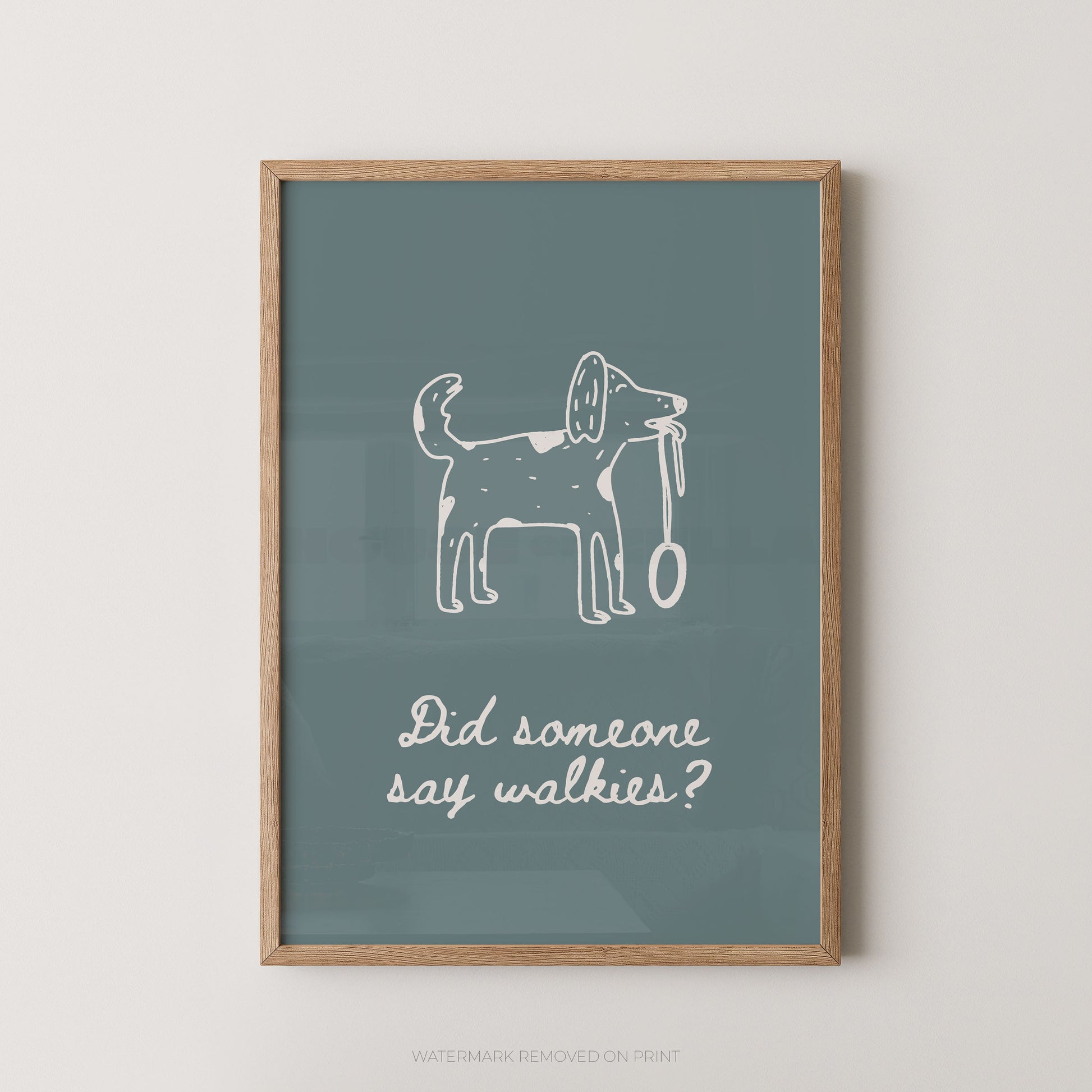 A framed wall art print with a muted blue-green background, a white line drawing of a dog holding a leash, and the phrase 'Did someone say walkies?' in white script. The print is shown in a light wood frame against a plain light wall.