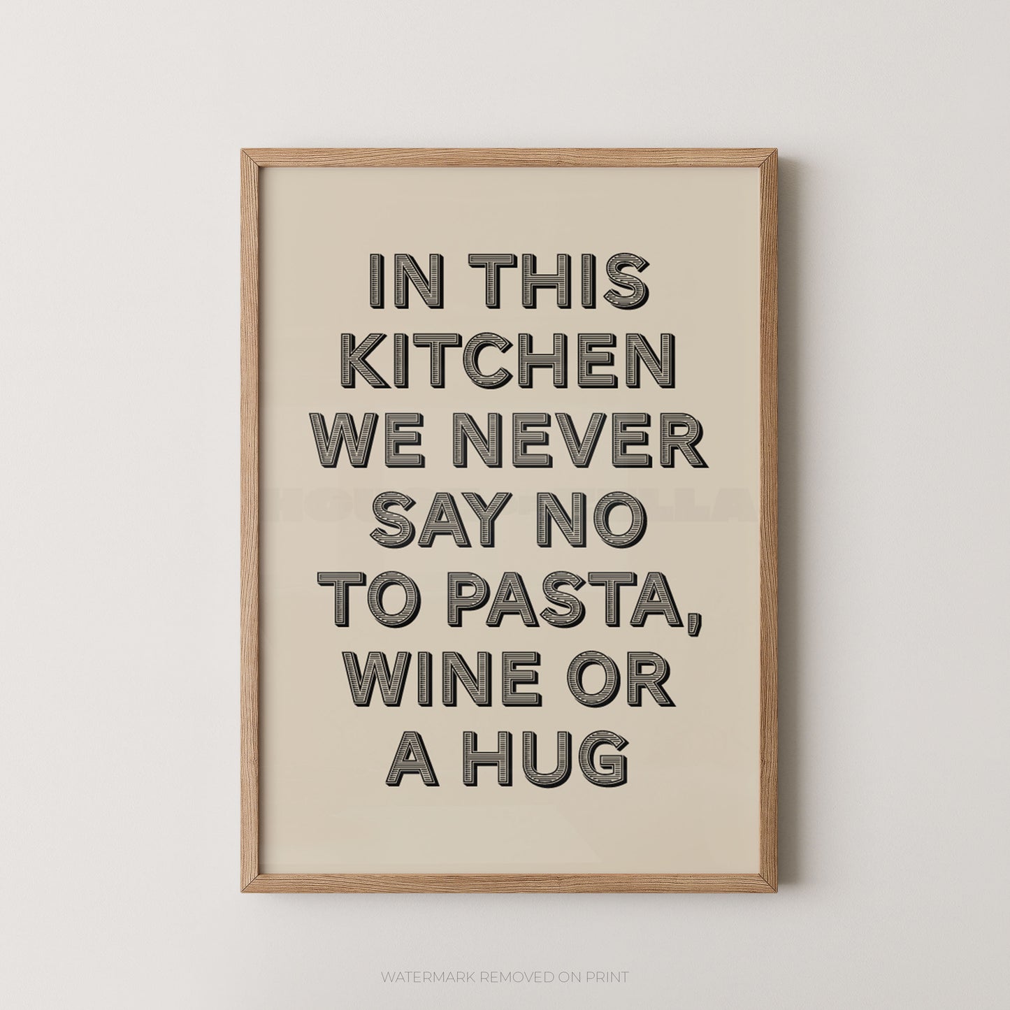 A framed typographic wall art print with the phrase “IN THIS KITCHEN WE NEVER SAY NO TO PASTA, WINE OR A HUG” in dark gray letters on a warm cream background, shown hanging against a light neutral wall.