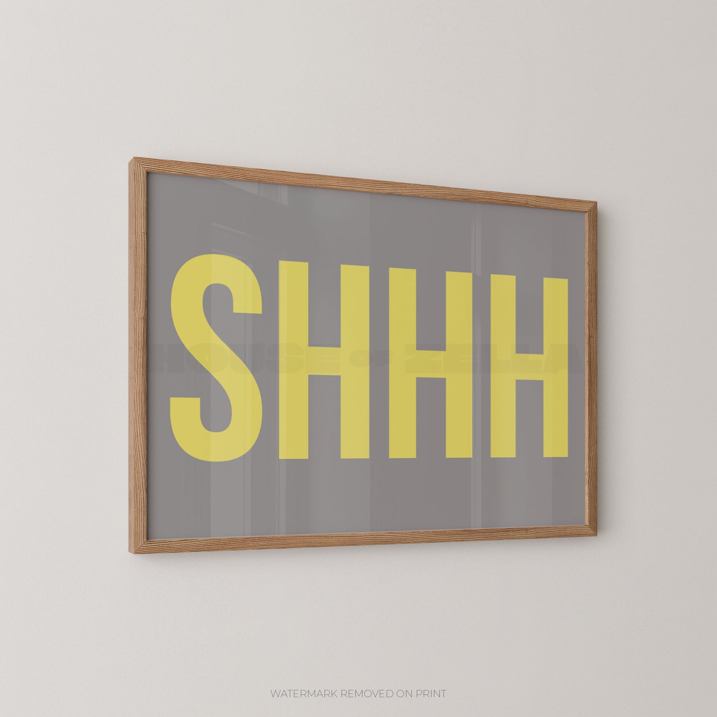 Framed wall art print with the word 'SHHH' in large yellow letters on a gray background, shown hanging on a light gray wall.