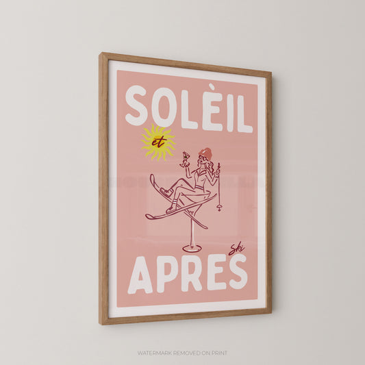 A framed art print featuring a retro illustration with the French text 'SOLÉIL et APRES' on a dusty pink background. The print includes a yellow sun and a line-drawn figure sitting on skis, all enclosed in a light wood frame and displayed on a neutral light gray wall.
