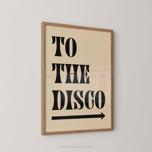 Framed wall art print with the words “TO THE DISCO” in large black stencil-style lettering and a black arrow below, shown hanging on a light gray wall.