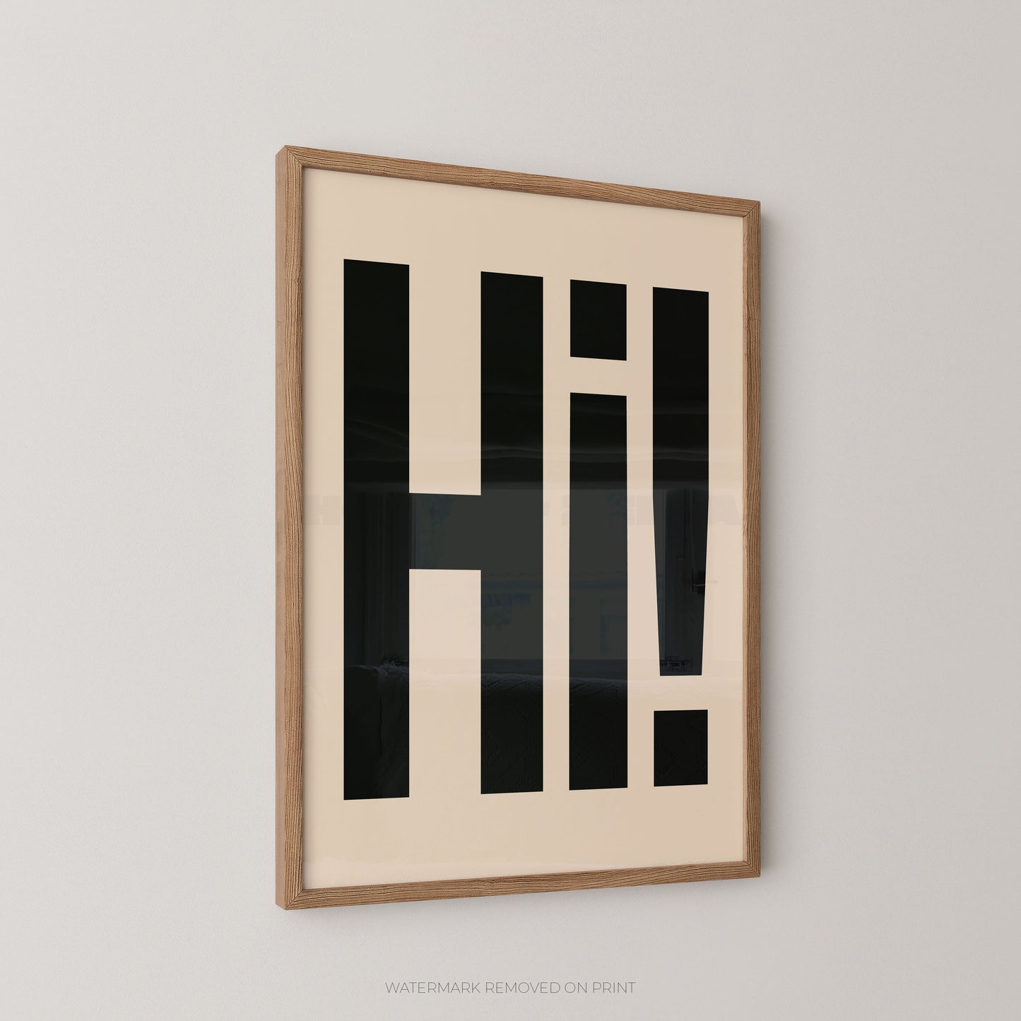 Framed wall art featuring bold black geometric lettering spelling 'HI!' on a cream background, shown hanging on a light gray wall.