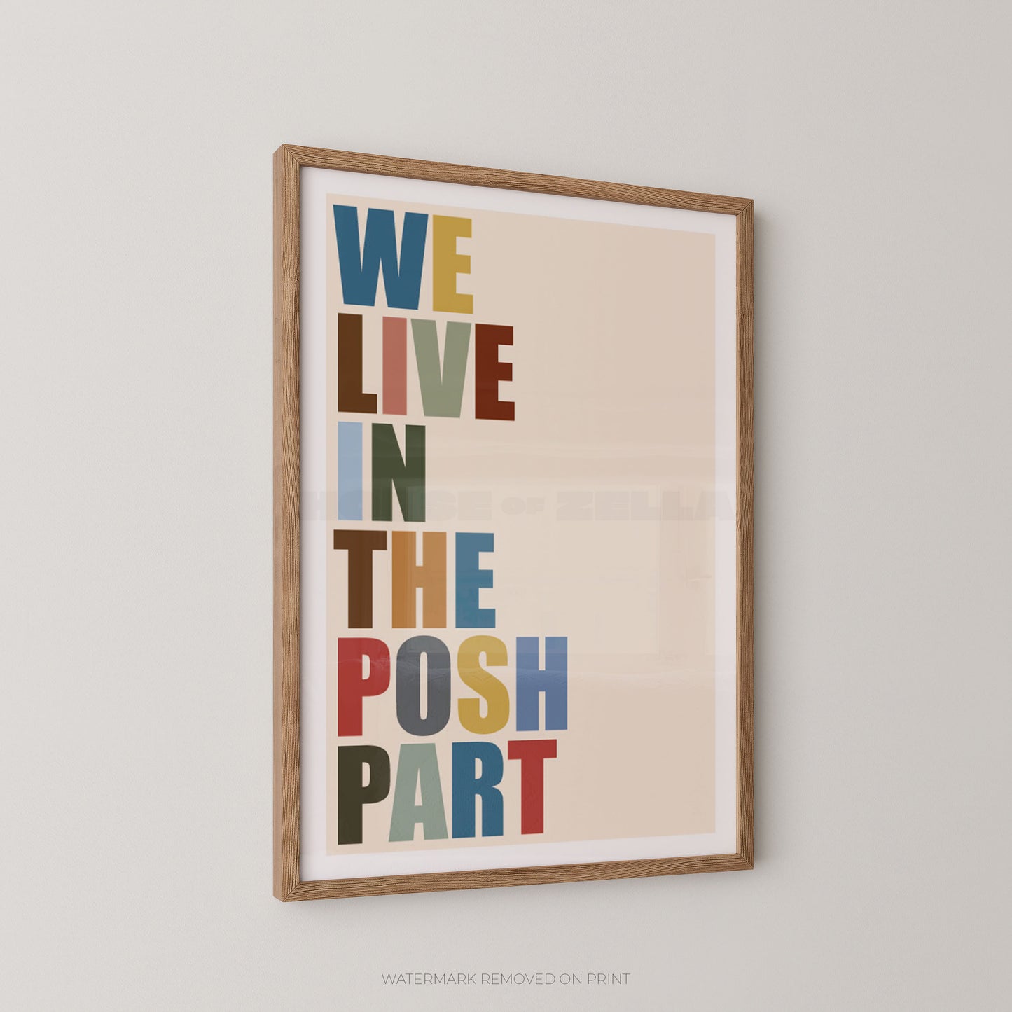 Framed typographic wall art hanging on a light gray wall, featuring the phrase “WE LIVE IN THE POSH PART” in large multicolored letters on a warm beige background.