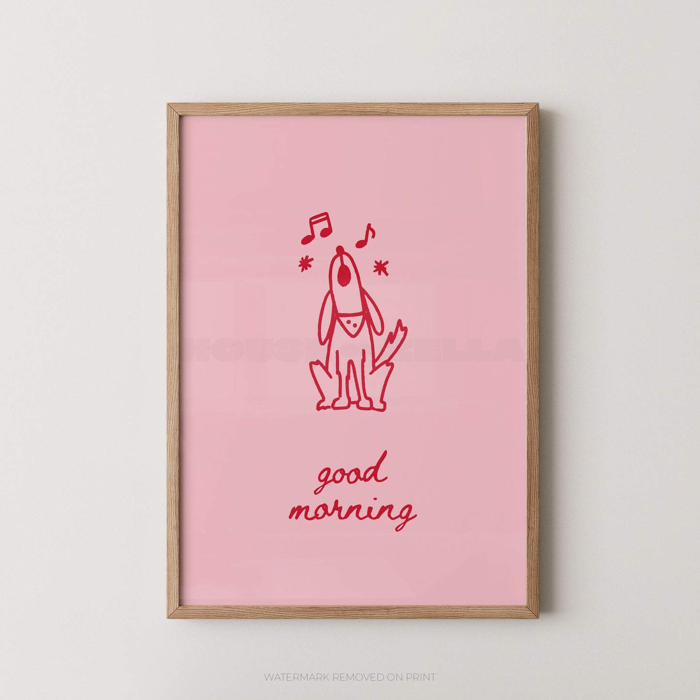 A framed art print featuring a pink background with a red line drawing of a dog, musical notes, and the words 'good morning' in red script, displayed against a light gray wall.