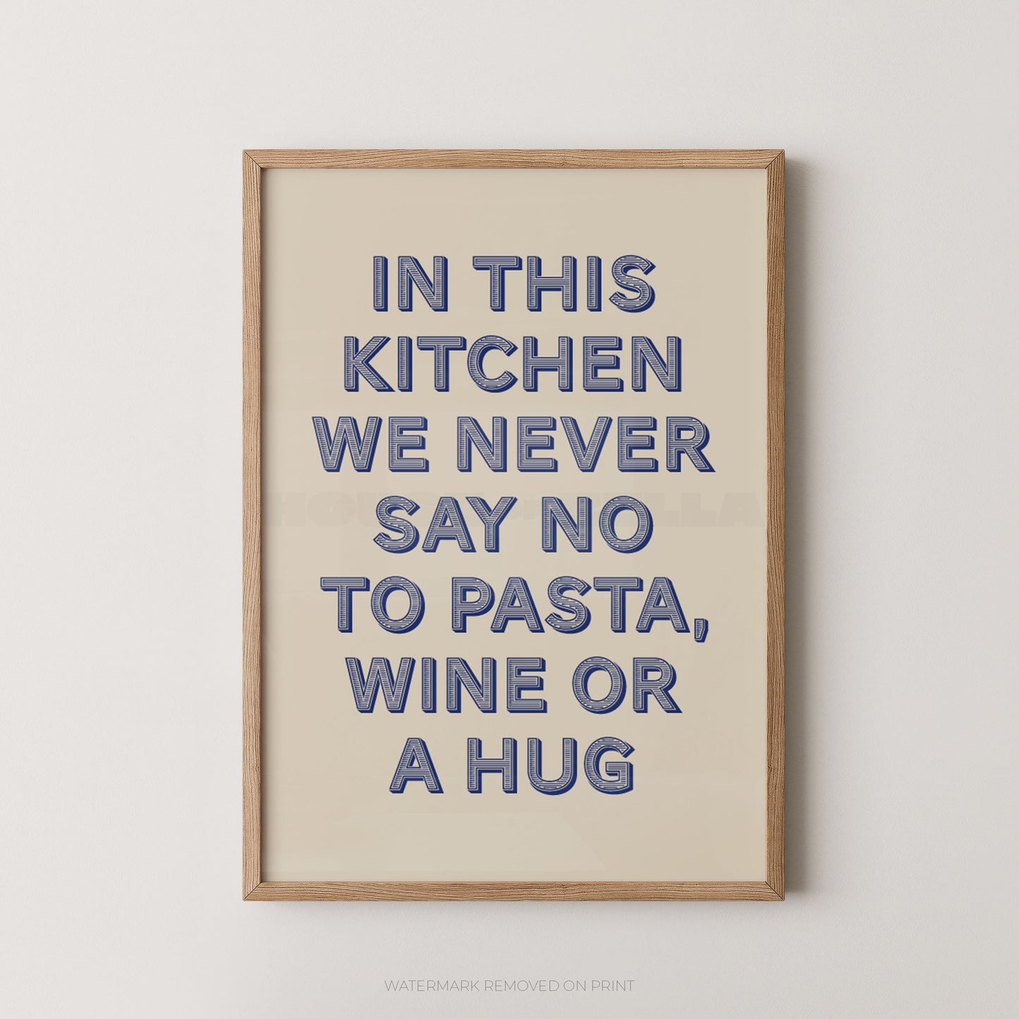 A framed typographic wall art print with the phrase “IN THIS KITCHEN WE NEVER SAY NO TO PASTA, WINE OR A HUG” in blue raised letters on a warm cream background, shown against a light neutral wall.